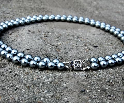 A strand of round pearls laid out on a stone surface.